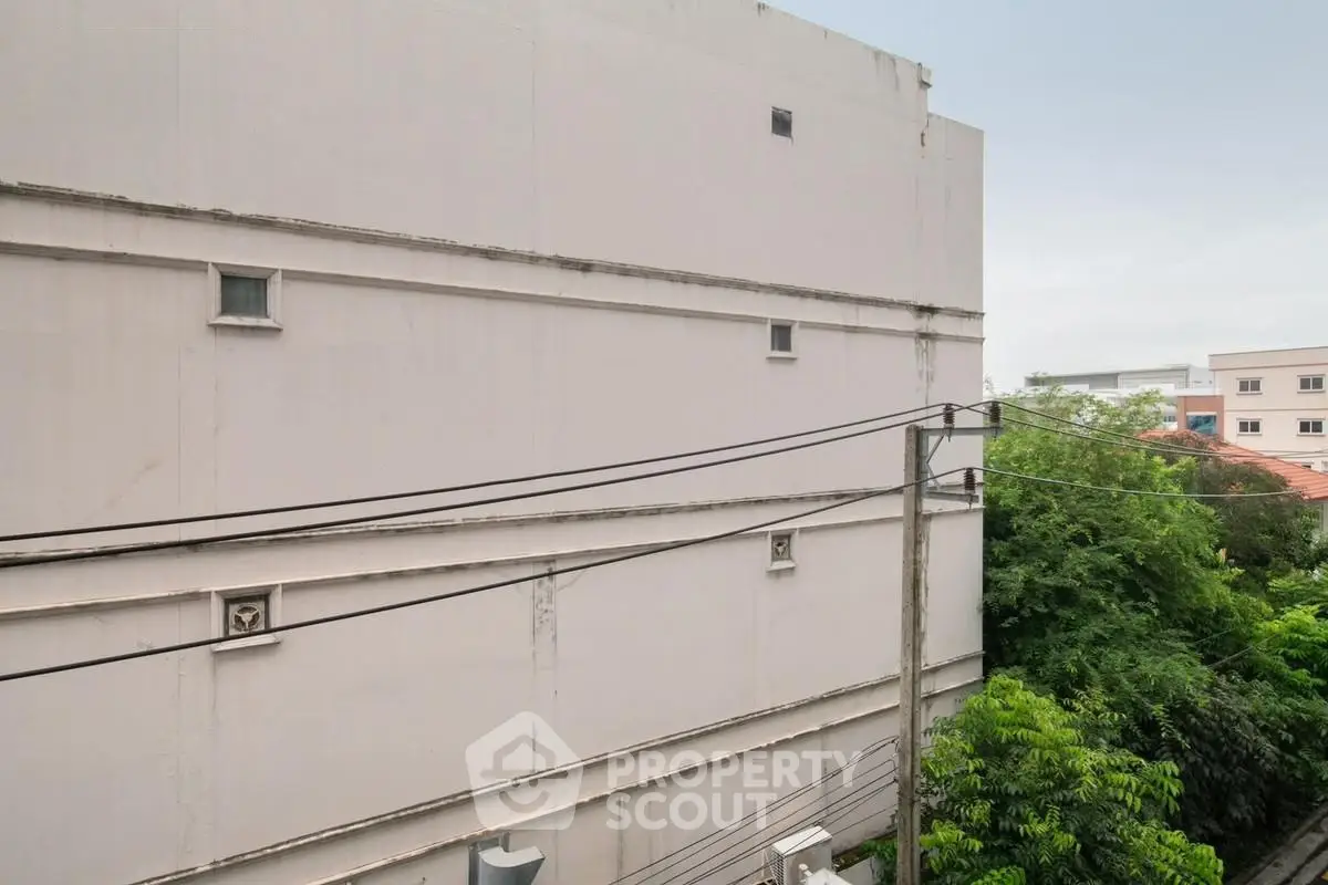 Urban building exterior with minimalistic design and lush greenery view.