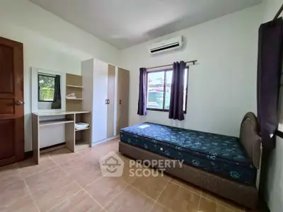 Cozy bedroom with single bed, wardrobe, and air conditioning in a bright, minimalist design.