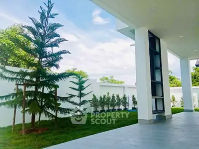 Modern home exterior with lush garden and spacious patio, perfect for outdoor relaxation.