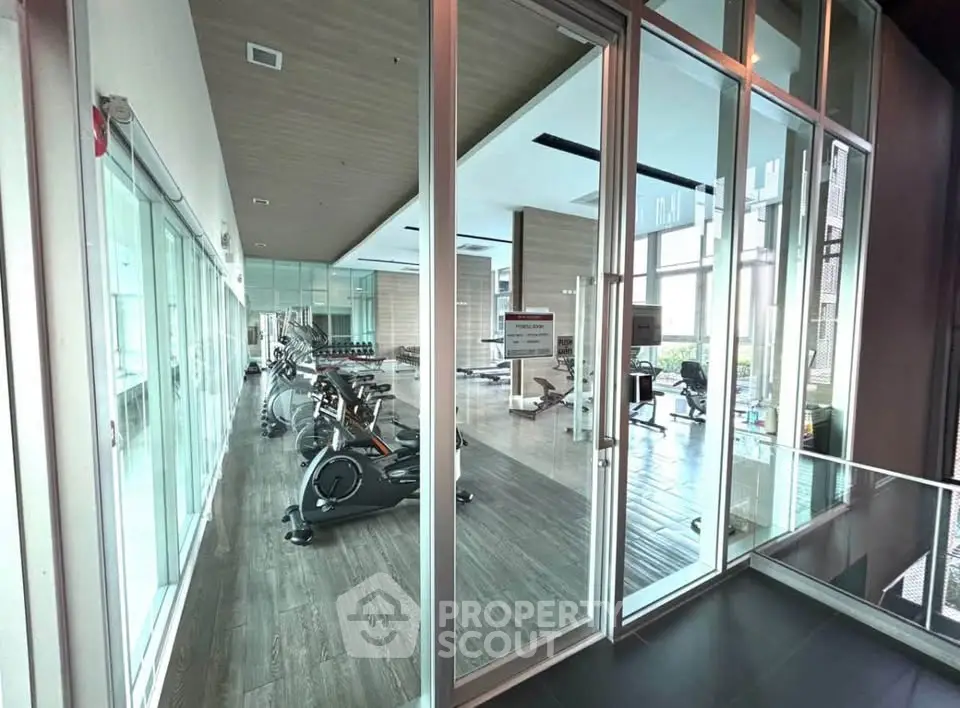 Modern gym with glass walls and exercise equipment in luxury building