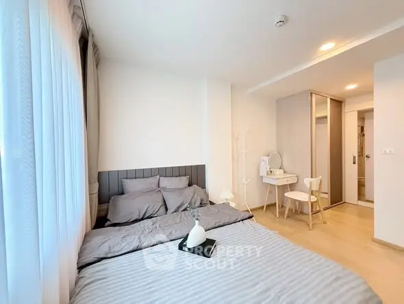 Modern bedroom with cozy decor and ample natural light in a stylish apartment.
