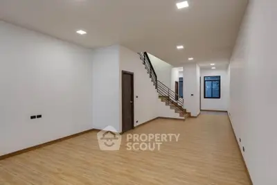 Spacious modern interior with wooden flooring and staircase, ideal for customization.