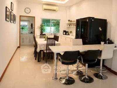 Spacious modern kitchen with sleek black fridge and elegant dining area
