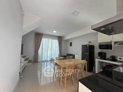 Modern open-plan kitchen and dining area with natural light and sleek furnishings.
