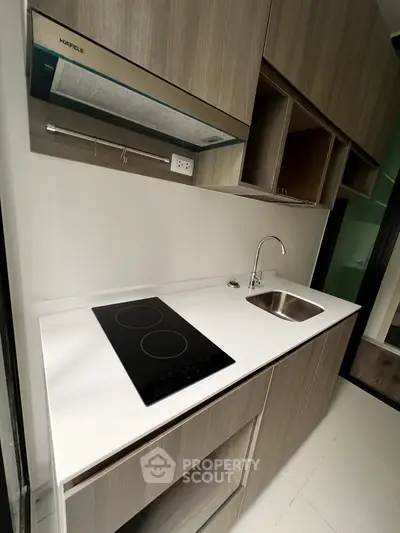 Modern kitchen with sleek cabinetry and electric cooktop in contemporary apartment