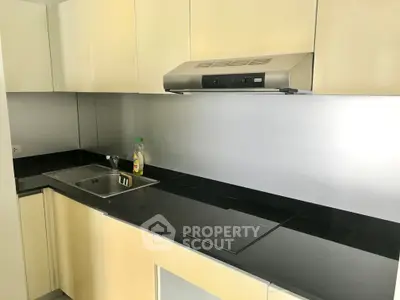Modern kitchen with sleek black countertops and stainless steel appliances in a contemporary apartment.