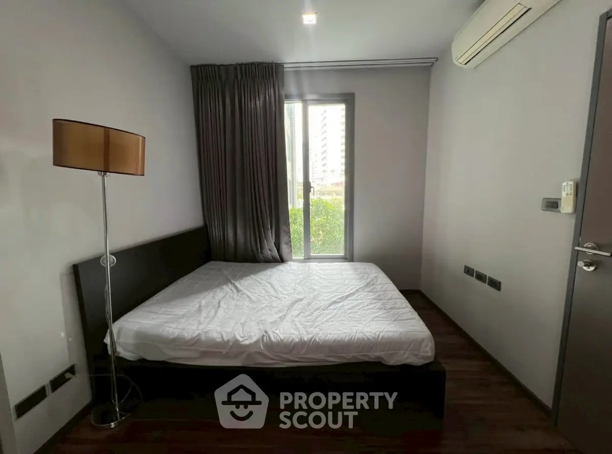 Modern bedroom with large window and air conditioning in urban apartment