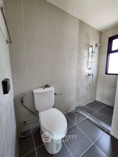 Modern bathroom with sleek tiles and walk-in shower in contemporary apartment.