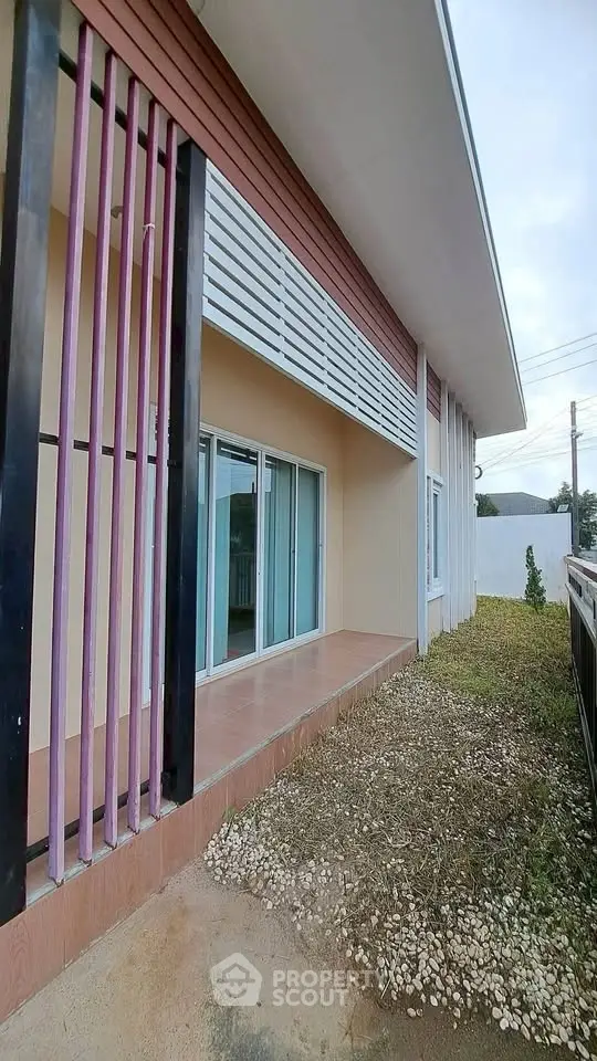 Modern single-story house exterior with sliding glass doors and stylish vertical slats.