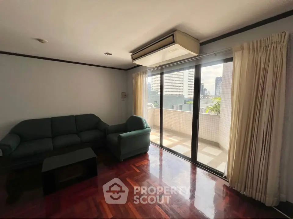 Spacious living room with large balcony and city view, perfect for urban living.