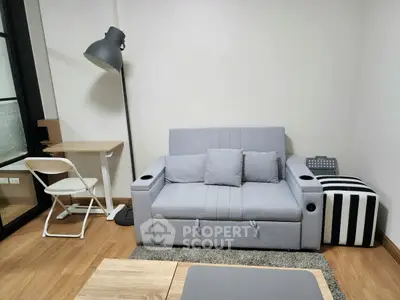 Modern living room with stylish gray sofa, chic floor lamp, and cozy workspace.