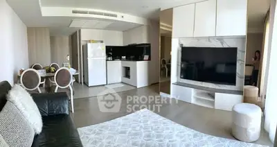 Modern living room with open kitchen, featuring sleek furniture and large TV, perfect for contemporary living.