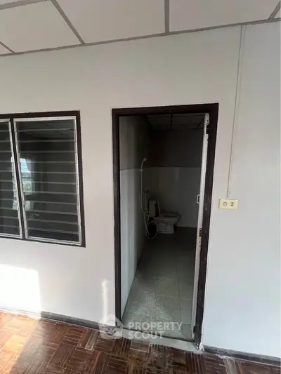 Compact bathroom with basic fixtures and adjacent window, ideal for minimalist living spaces.