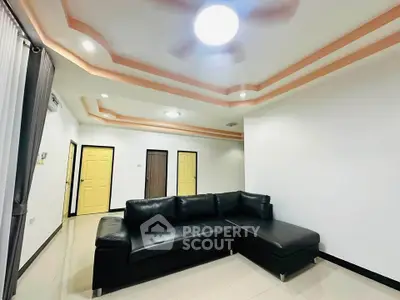 Spacious modern living room with black leather sectional sofa and stylish ceiling lights.