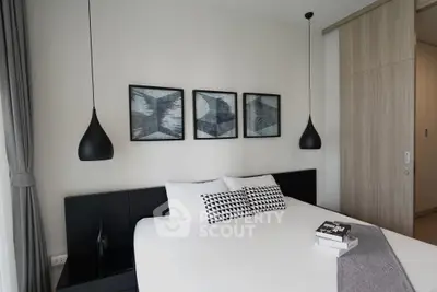 Modern bedroom with stylish decor and pendant lighting, featuring a comfortable bed and elegant artwork.