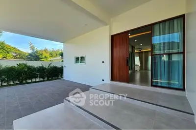 Modern home entrance with spacious tiled patio and sliding glass doors.
