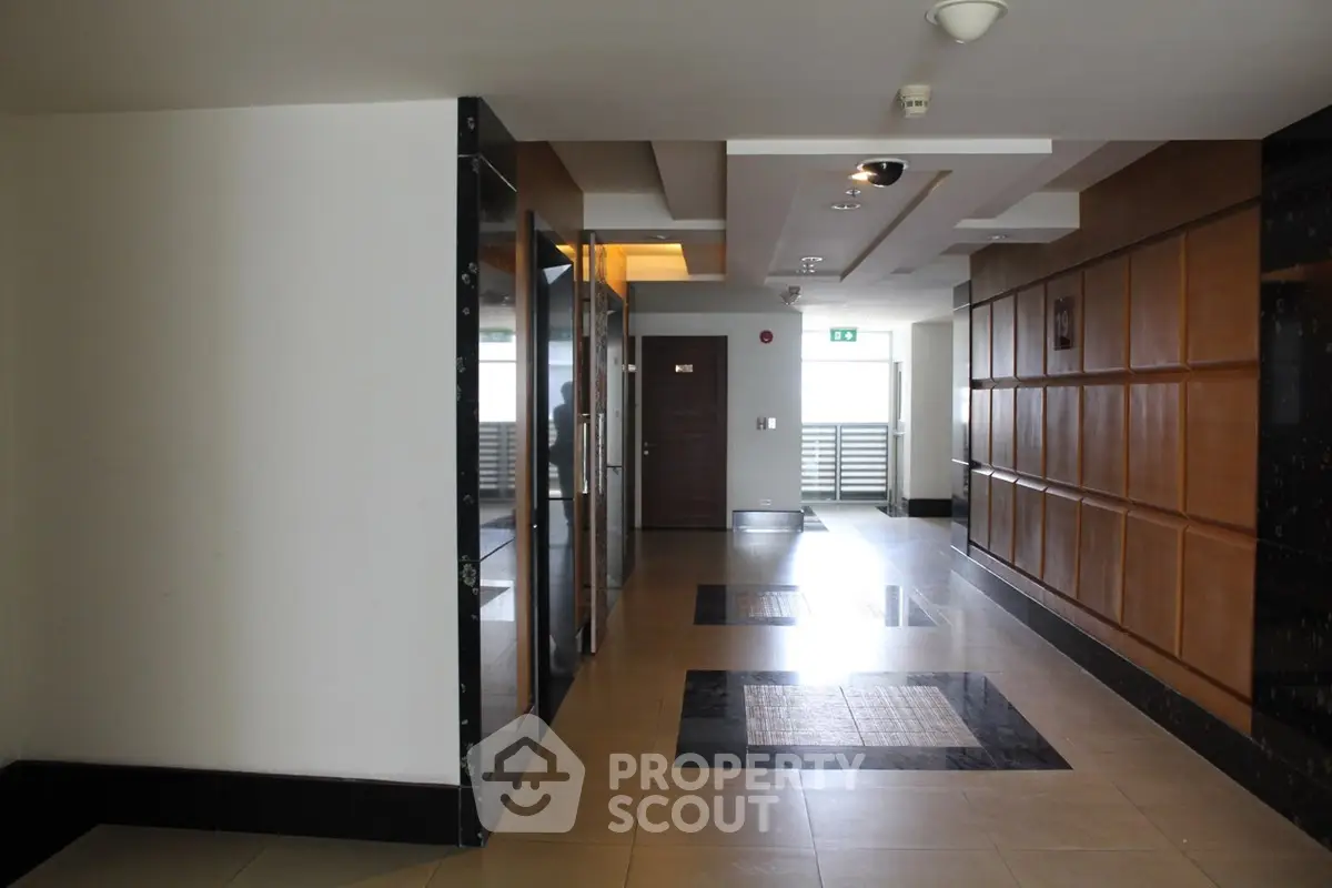 Modern apartment building corridor with stylish wooden paneling and sleek tile flooring.