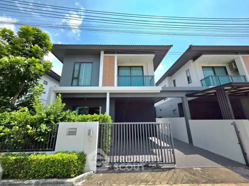 Modern two-story house with gated driveway and lush greenery, perfect for family living.