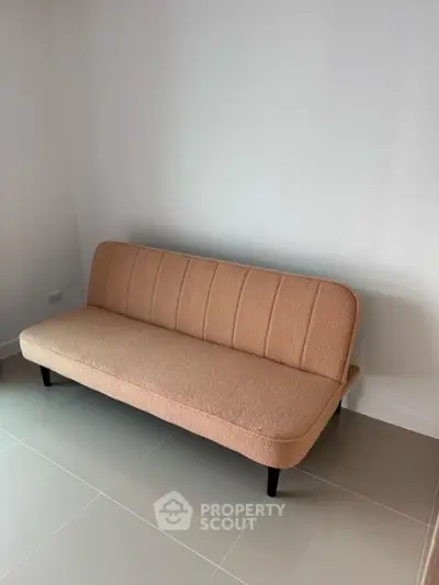 Minimalist living room with a modern beige sofa on tiled flooring.