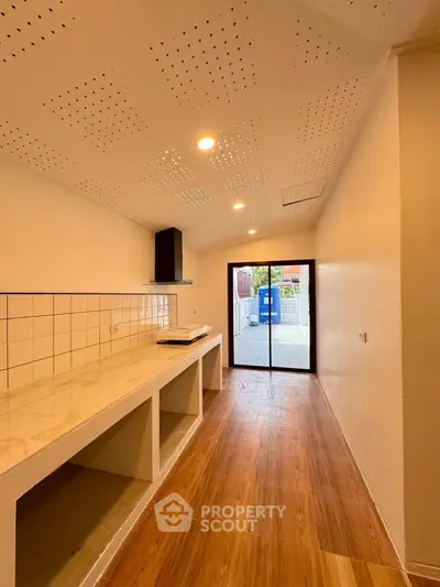Modern kitchen with open layout and sleek design, featuring wooden flooring and ample natural light.