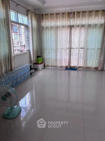 Spacious living room with large windows and elegant curtains, perfect for natural light.