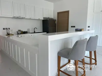 Modern kitchen with sleek white cabinetry and breakfast bar seating