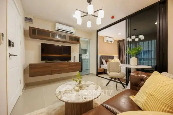 Modern living room with stylish decor and open view to bedroom, featuring cozy seating and elegant lighting.