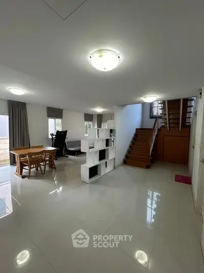 Spacious modern living room with open layout, dining area, and stylish staircase in a contemporary home.