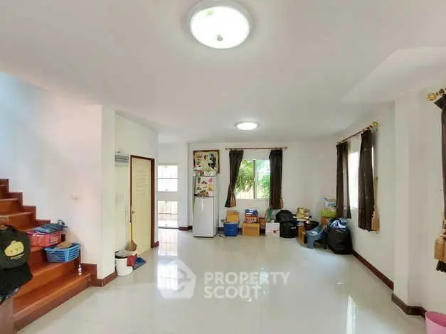 Spacious living room with natural light and staircase, ideal for family gatherings.