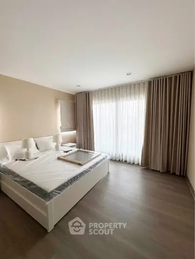 Spacious bedroom with large window and elegant curtains, perfect for natural light lovers.