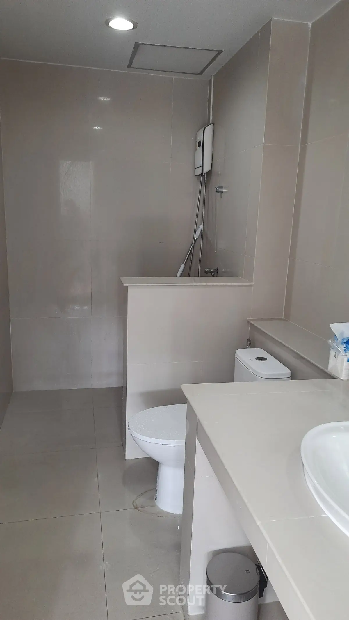 Modern bathroom with sleek design and neutral tones, featuring a shower and toilet.