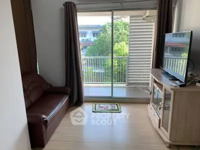 Cozy living room with balcony view, featuring a comfortable sofa and modern TV setup.