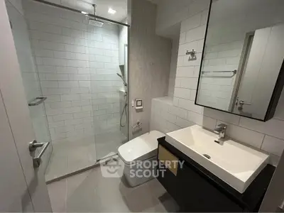 Modern bathroom with sleek fixtures and glass shower enclosure in contemporary apartment.