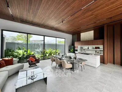 Luxurious open-plan living and dining area with modern furnishings and large windows overlooking greenery.