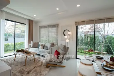 Spacious modern living room with large windows and garden view, featuring cozy seating and elegant decor.