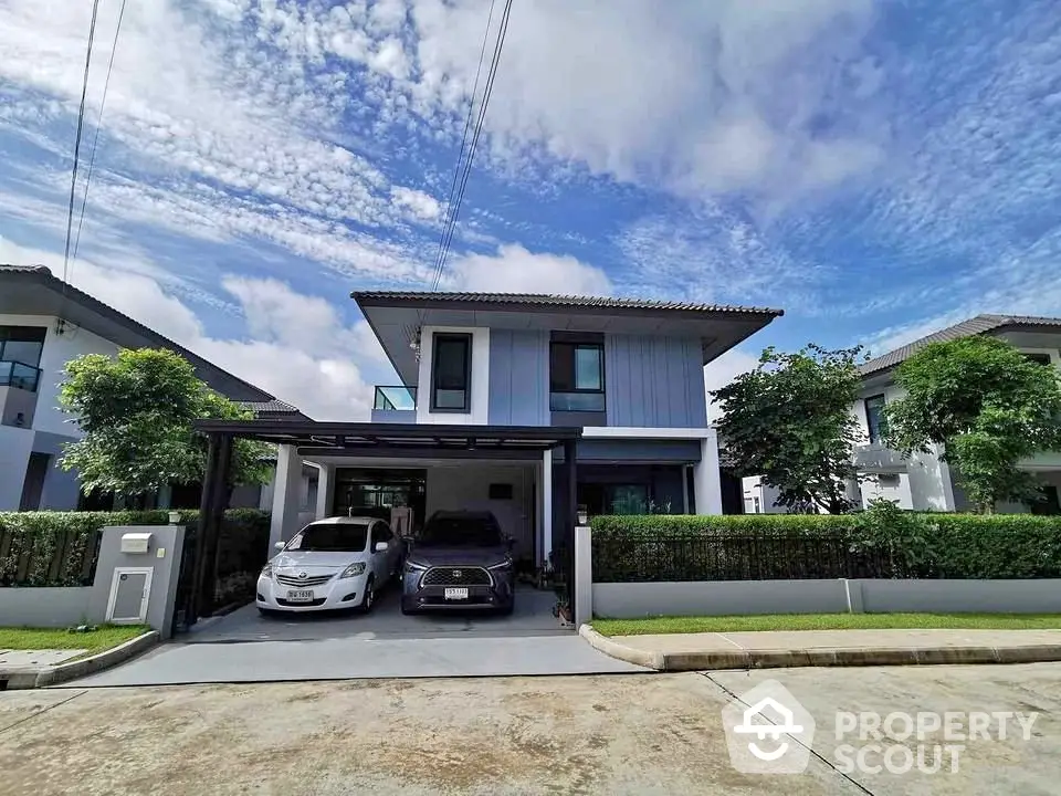 Modern two-story house with driveway and lush greenery in a serene neighborhood.