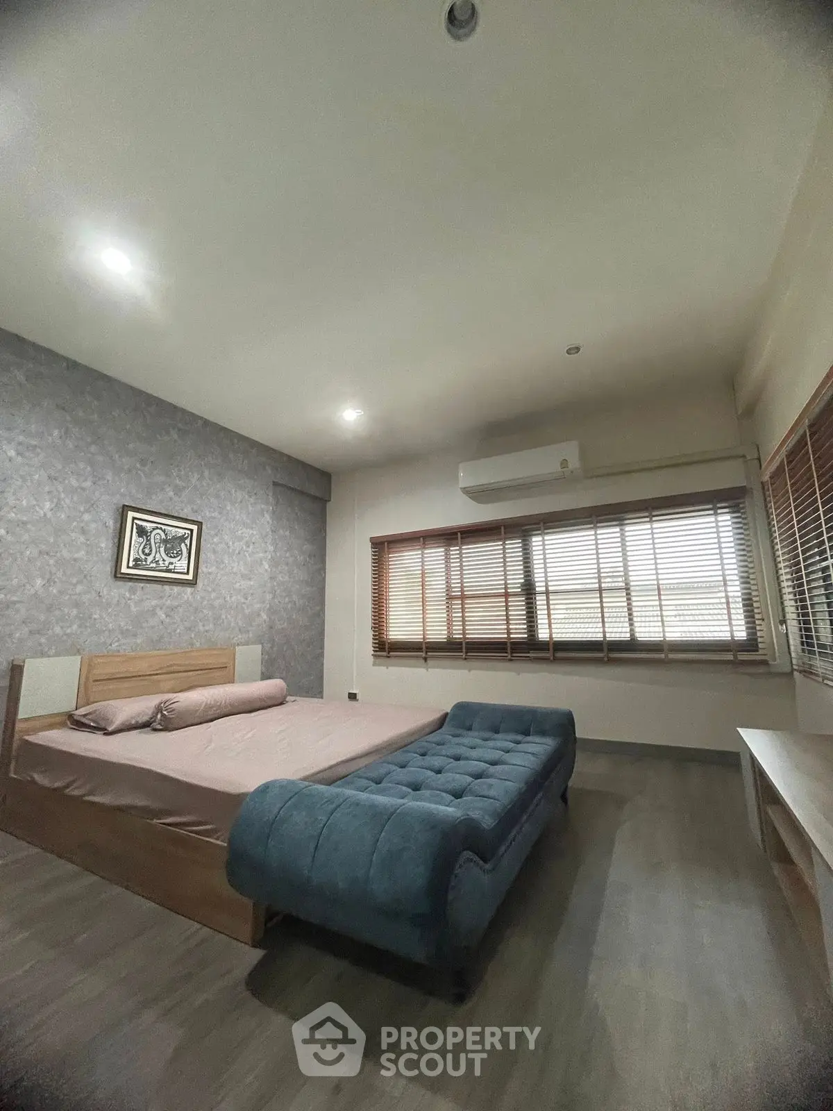 Spacious bedroom with modern decor and large windows for natural light.