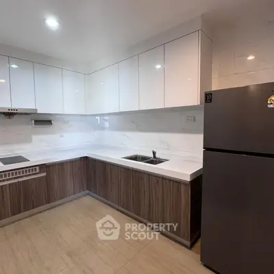 Modern kitchen with sleek cabinetry and stainless steel fridge in a contemporary apartment.