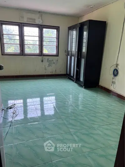 Spacious empty room with tiled floor and large windows, ideal for customization.