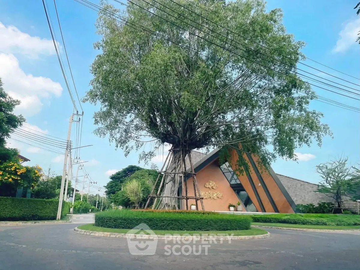 Modern architectural building with unique design surrounded by lush greenery and clear blue sky.