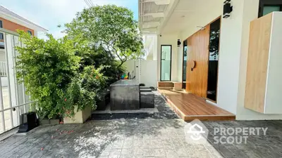 Modern home entrance with stylish wooden door and lush greenery