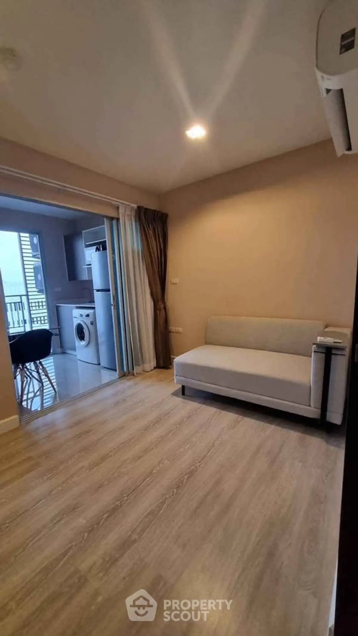Modern living room with open kitchen and balcony view, featuring sleek furniture and wooden flooring.