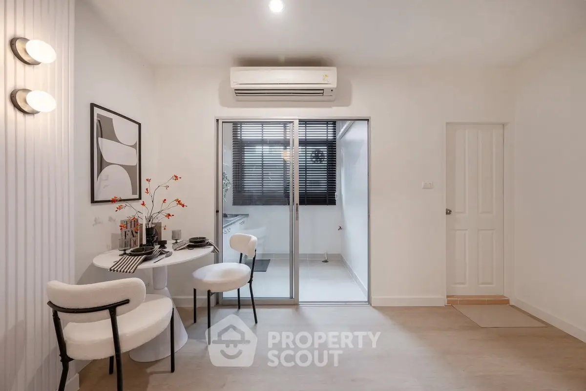 Modern dining area with stylish decor and air conditioning, featuring a cozy table setup and sliding glass doors.