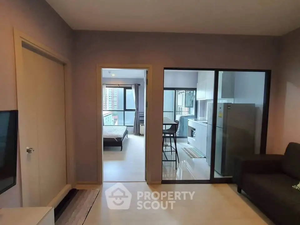 Modern apartment interior with open layout connecting living room, kitchen, and bedroom.