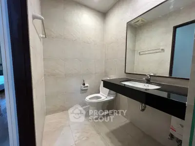 Modern bathroom with sleek black countertop and large mirror in a contemporary home.