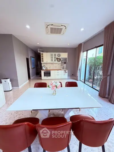 Spacious modern kitchen with open layout and elegant dining area, featuring large windows and stylish decor.