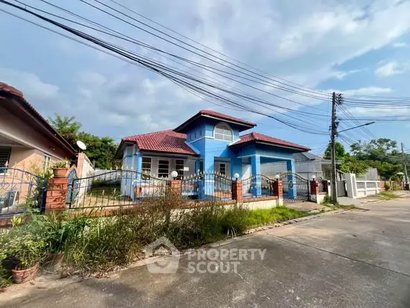 Charming blue house with red roof and fenced yard in a serene neighborhood.
