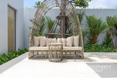 Stylish outdoor patio with modern wicker furniture and lush greenery