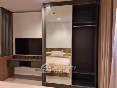 Modern bedroom with mirrored wardrobe and wall-mounted TV, featuring sleek design and cozy ambiance.