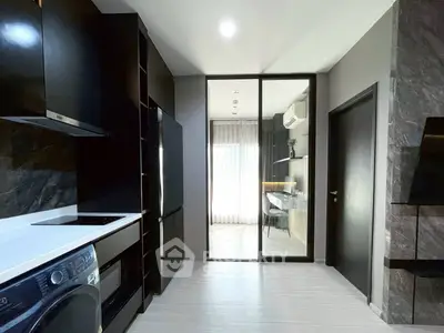 Modern kitchen with sleek black cabinetry and appliances, featuring a washing machine and open layout.